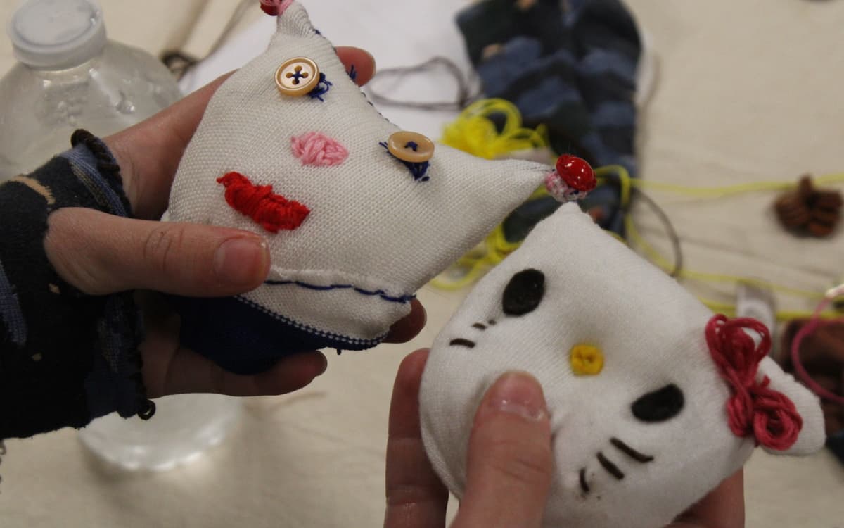Photographies de deux mains tenant des peluches qui ont été réalisées à partir de chaussettes, avec des boutons et des fils de couleurs.