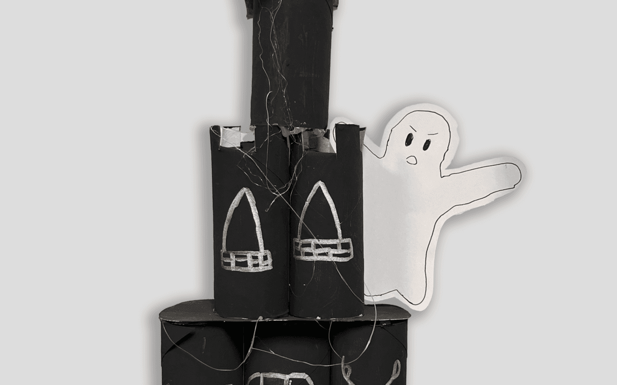 Un château hanté fabriqué et construit à la main. Le château est noir avec des détails blancs et un fantôme fait en papier.